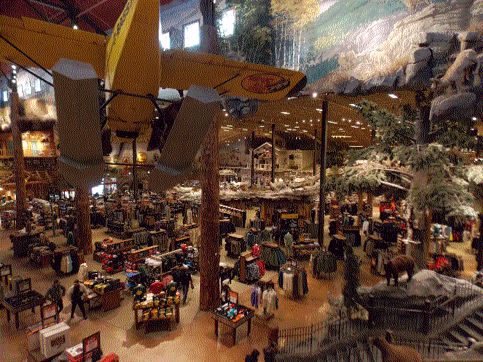 A photo of the store floor from above. There is a yellow plane hanging from the ceiling, with the Bass Pro Shop logo on its wing.