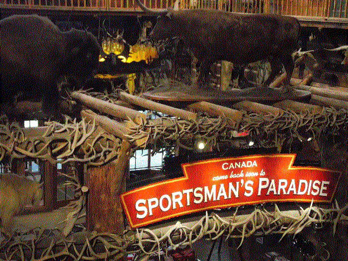 the front sign of the store, which is a wooden structure adorned with antlers. The sign reads Canada, Come back soon to Sportsman's paradise.