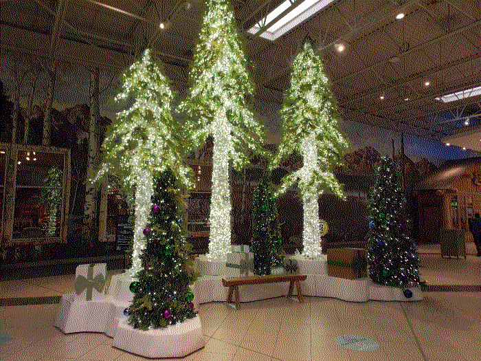 A small christmas display, of fake trees glittering with lights around a bench.