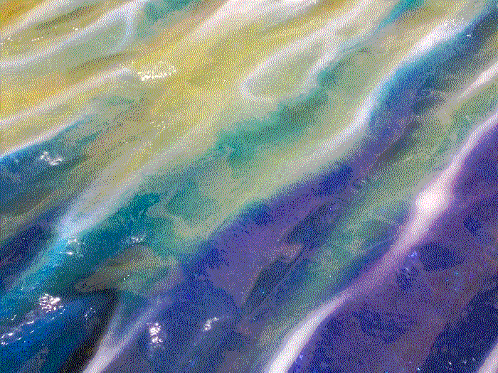 A closeup of the waters, which fade from yellow, to green, to blue. There are faint sparkles under the gloss.